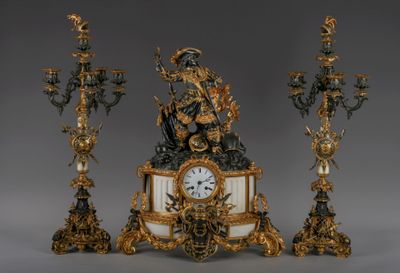 a clock with a statue on top of it next to three candles