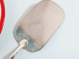 a red spatula with a handle on a white surface