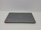 the dell laptop is sitting on a white table with a pink sticker on it