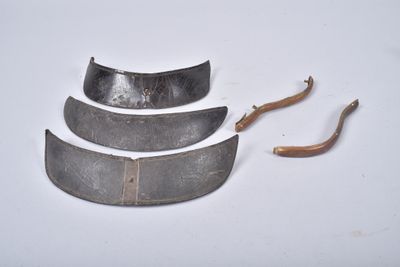 four pieces of metal on a white surface with a wooden handle