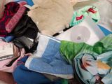 a pile of clothes and a teddy bear on a bed