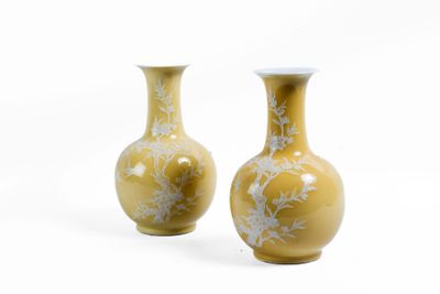 une paire de vases jaunes ornés de fleurs blanches sur fond blanc