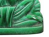 a green statue of a man with a book in his lap