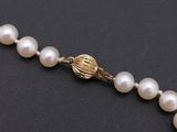 a close up of a pearl necklace on a black surface