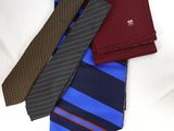 three ties and a wallet on a bed with a white sheet