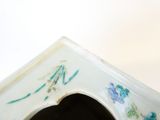un vase blanc orné de fleurs bleues et vertes