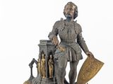 a clock with a statue of a man holding a shield