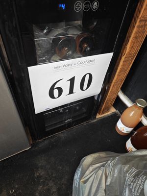 une bouteille de vin et une bouteille de bière à côté d'un réfrigérateur