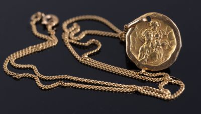 a close up of a gold coin on a chain on a black surface
