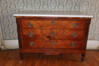 une commode en bois avec un plateau en marbre posée sur un parquet en bois dur