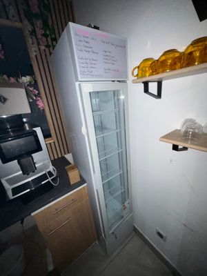 a refrigerator in the corner of a kitchen with a shelf above it
