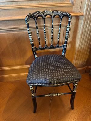 chaise peinte en noir et or dans une pièce aux murs lambrissés