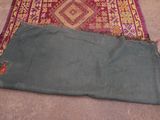 a rug on the floor with a green bag on top of it