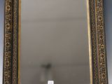 un miroir au cadre doré ouvragé posé sur une table blanche