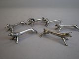 four silver dog figurines on a white surface