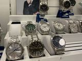 many watches on display in a store with a picture of a man in the background