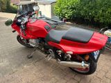 a red motorcycle parked next to a trailer in a driveway