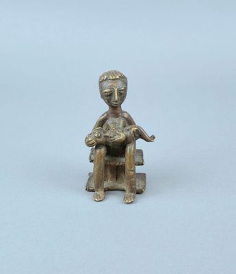 figurine en bronze représentant un enfant assis sur une chaise, tenant un chat dans ses bras
