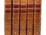 six vieux livres sont alignés sur une surface blanche