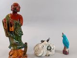 three figurines of a man and a bird on a table