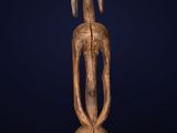 a wooden statue of a woman with a long neck and a long tail