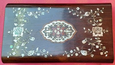 une boîte en bois ornée d'un motif sur un fond rose