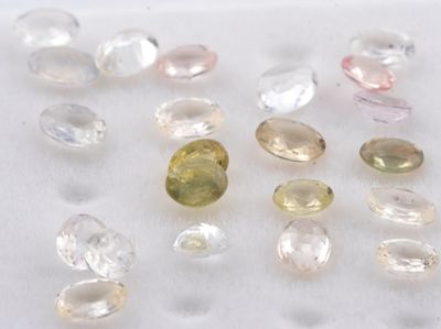 Plusieurs pierres précieuses de différentes couleurs sont disposées sur une surface blanche.
