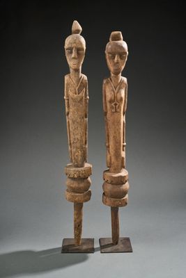 paire de figurines en bois sculpté posées sur un socle, sur fond gris