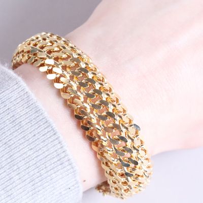 a woman wearing a gold chain bracelet on her wrist