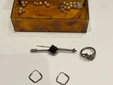a wooden box with a watch, a ring, and a pair of earrings on a table