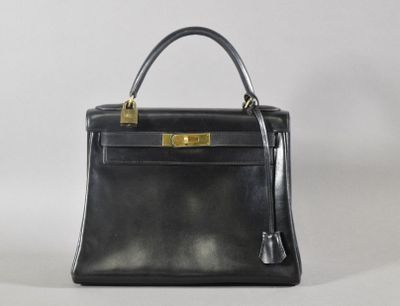 un sac à main en cuir noir avec des finitions dorées sur fond blanc