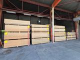de nombreuses piles de bois dans un entrepôt au toit métallique