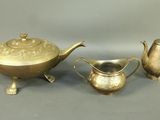 three pieces of silverware including a teapot, sugar and creamer
