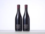 two bottles of red wine sitting on top of a table