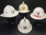 three white hard hats sitting on top of each other on a black surface