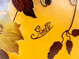 a yellow vase with a design of leaves on it