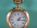 une montre de poche en or posée sur une table, sur fond vert