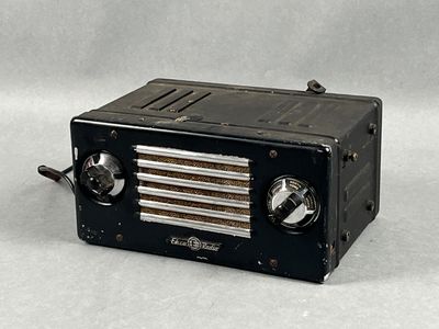 une radio noire posée sur une table, sur fond blanc