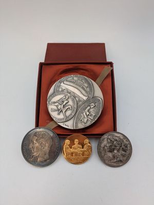 trois pièces d'argent et d'or dans une boîte rouge posée sur une surface blanche