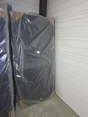 two mattresses wrapped up in plastic in a storage room