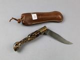 a knife that is laying on a table next to a leather case