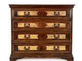 une commode ancienne dont les tiroirs sont ornés de motifs dorés et noirs