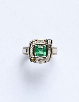 un gros plan d'une bague posée sur une surface blanche, ornée d'une pierre verte
