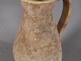 a small brown vase with a handle on a table