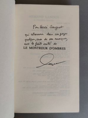 un livre ouvert, sur lequel figure une citation manuscrite, posé sur une table