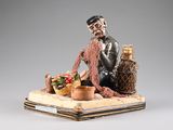 figurine of a man sitting on a table with a basket of fruit