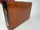 a person holding a brown leather briefcase on a white surface