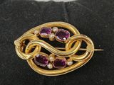 a close up of a gold and purple broochle on a black glove