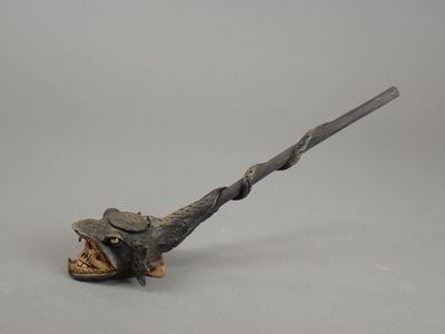 un petit objet métallique d'où sort un long bâton par la bouche
