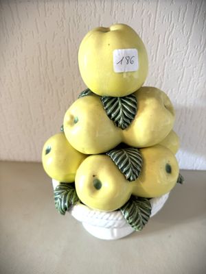 des pommes jaunes dans un bol blanc, accompagnées de feuilles vertes, posées sur une table